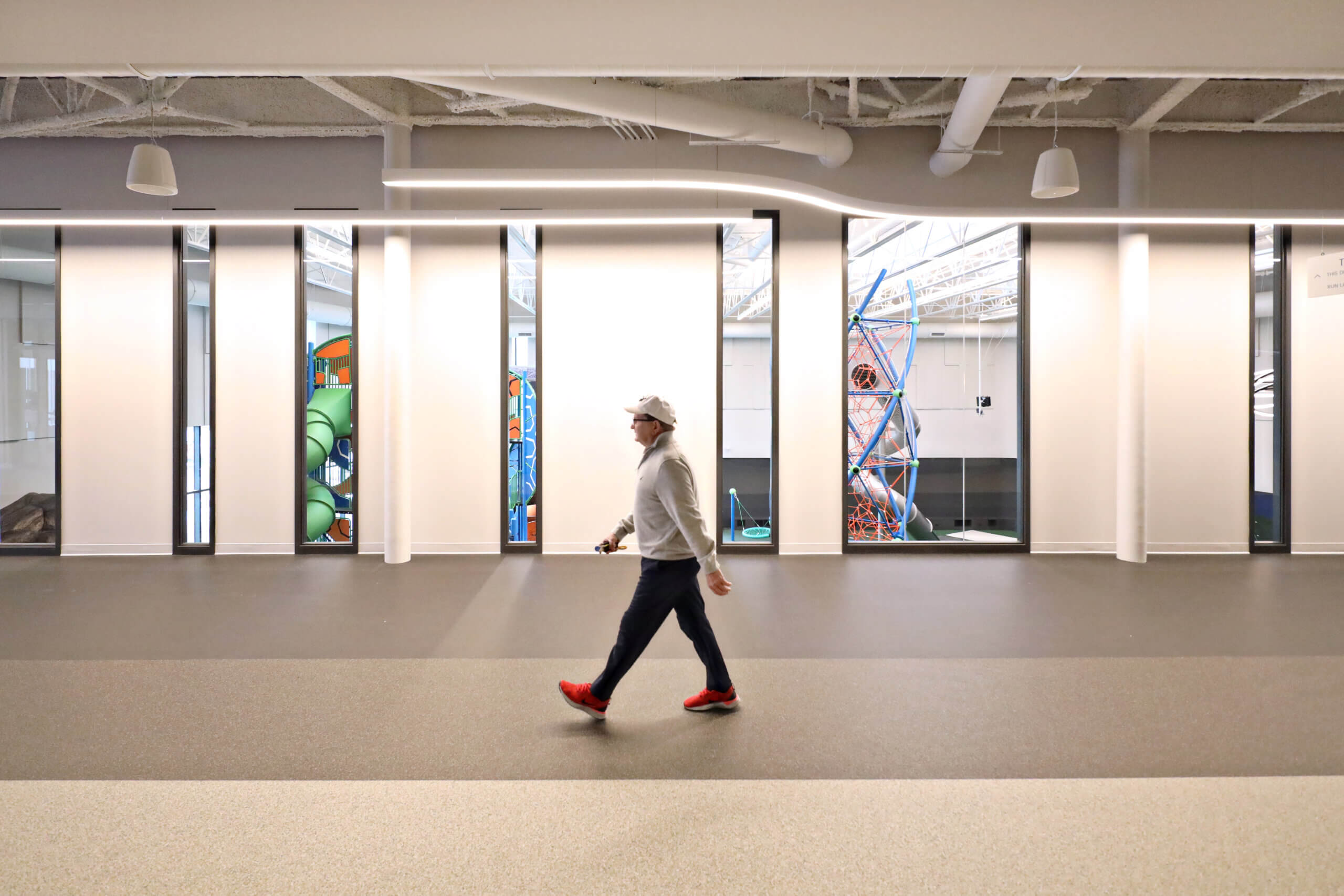 Person walking through a modern office hallway, passing by colorful, artistic doors.