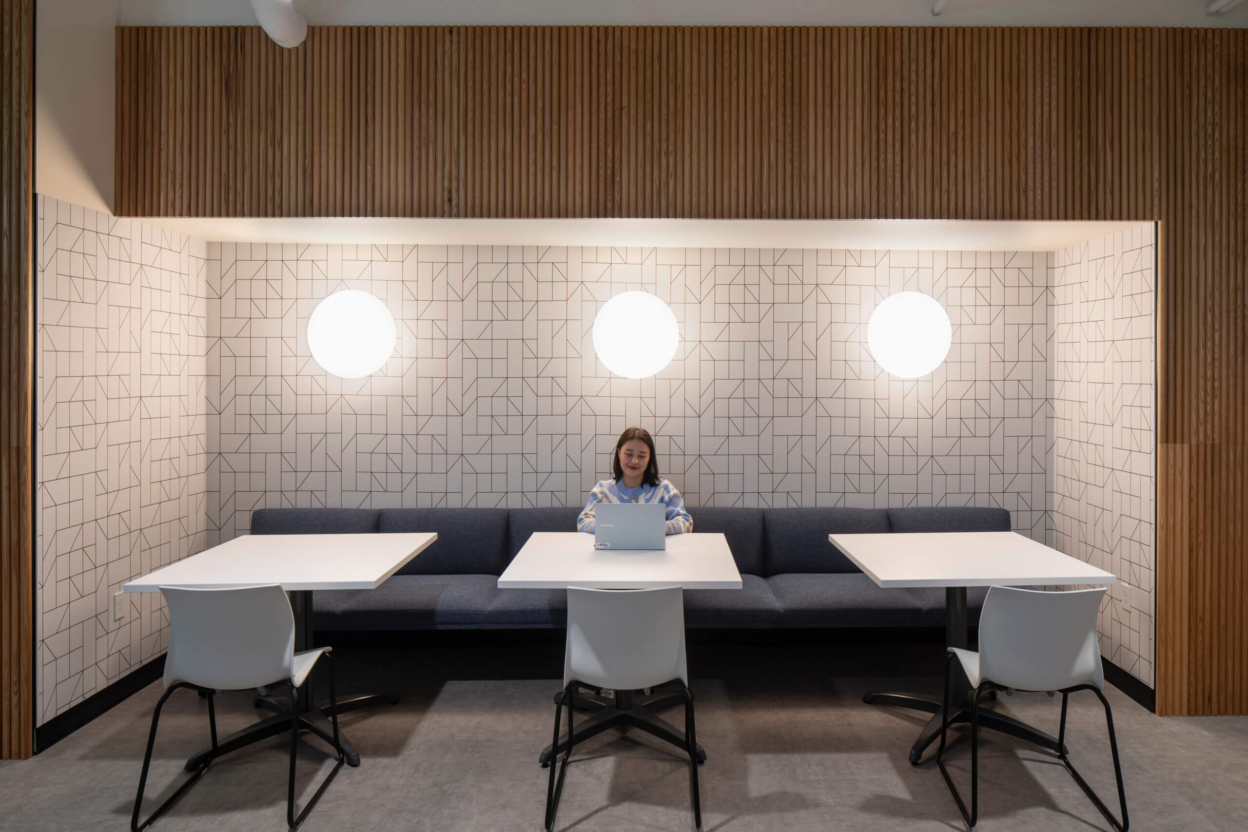An employee is working on a laptop in a versatile alcove with recessed lighting