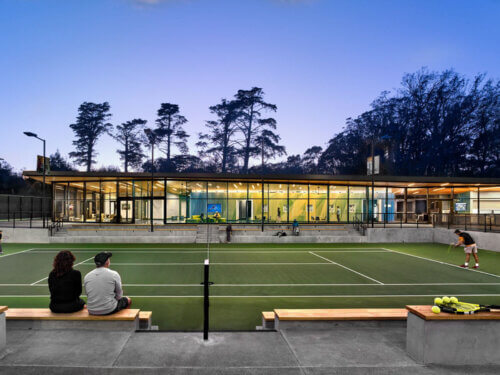 Courts with a view of the clubhouse at the Lisa and Douglas Goldman Tennis Center