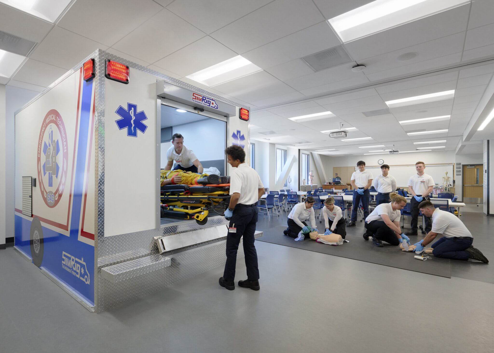Medical training facility where EMTs in training practice CPR and loading dummies into a model ambulance