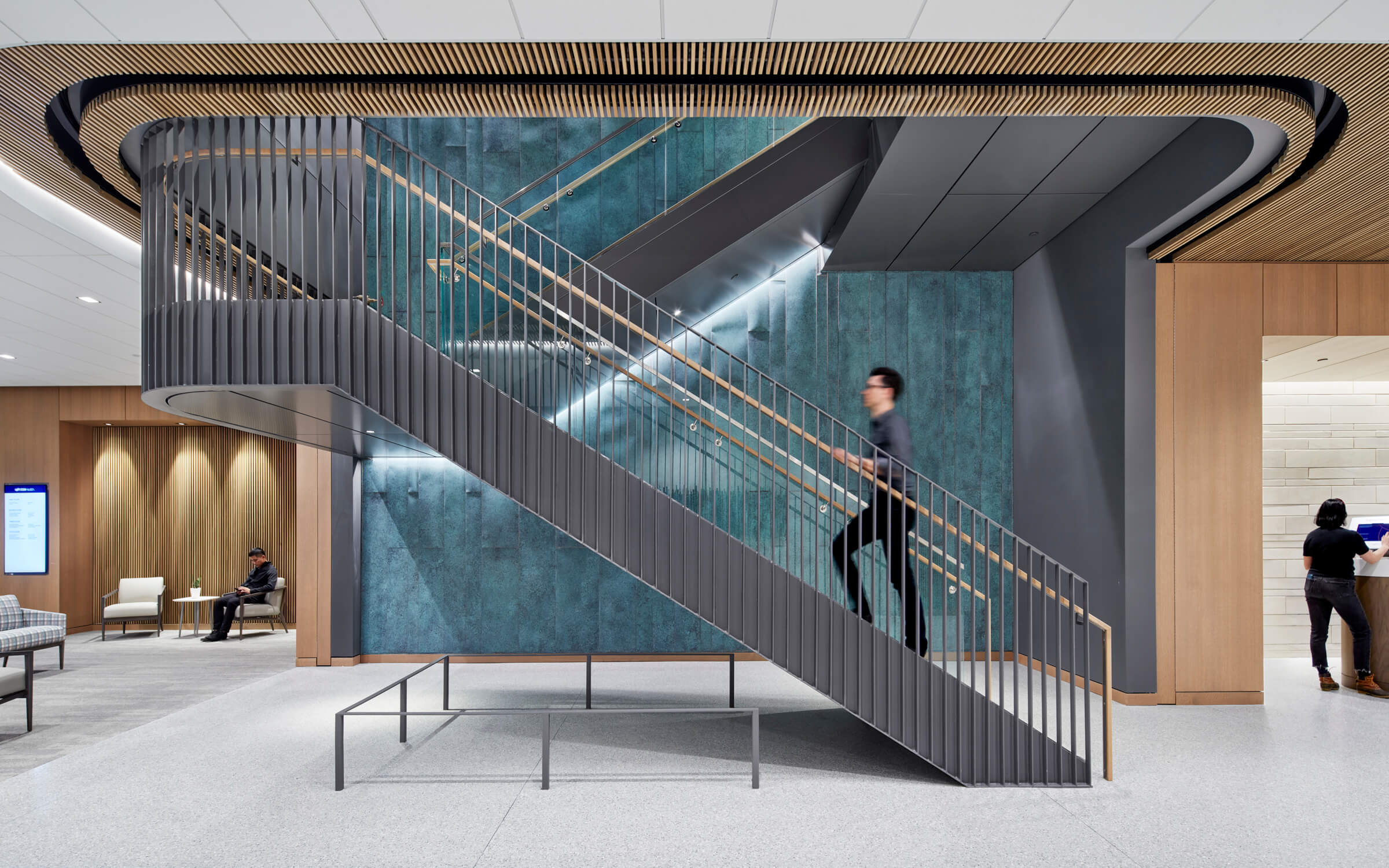 Person walking up a staircase in a modern building in front of a marble wall