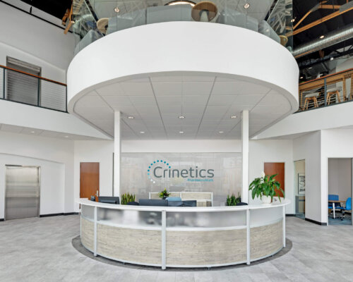 Lobby of a health sciences building with a reception desk with the Crinetics logo