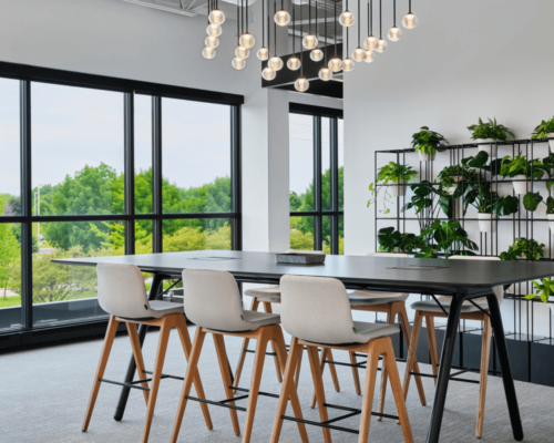 interior photo of long tables near windows with a plant wall behind and contemporary light fixture overhead